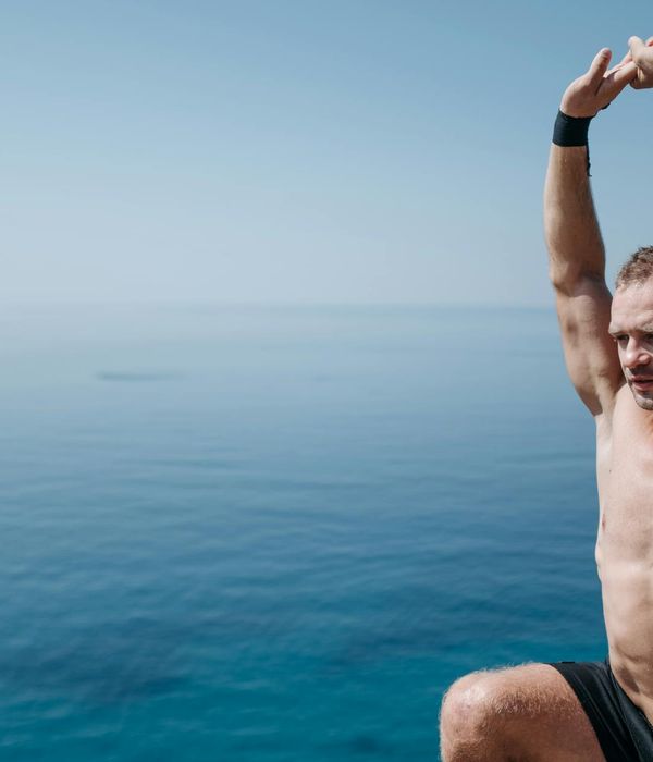 Person stretching gently outdoors with a serene natural background.